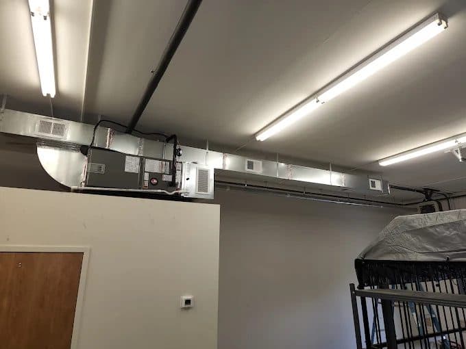 Commercial air handler with new exposed rectangular ductwork and diffusers installed in a shop space