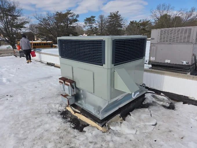 New commercial rooftop package unit installed by KelAire HVAC on a snow-covered flat roof on the upper Eastern Shore