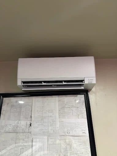 Ductless mini-split indoor head installed above framed drawings in a home office