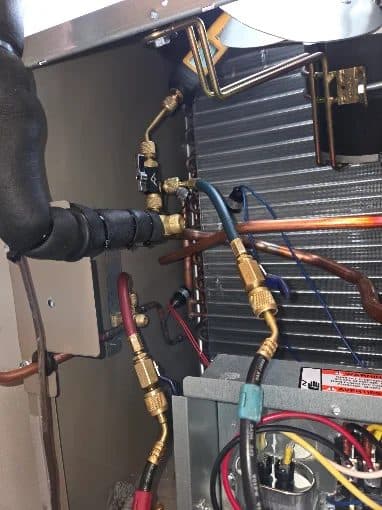Brazed copper refrigerant lines and service valves inside an HVAC unit during repair by KelAire